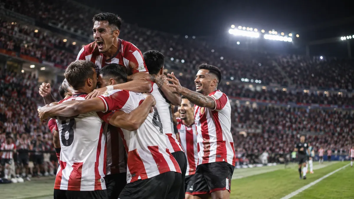 Futbolistas de un equipo rojiblanco celebran en un estadio durante un partido nocturno
